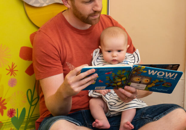 Man reading to baby in Wow said the Owl exhibition