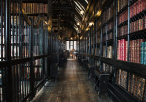 A wood panelled corridor with lined with shelves of antique books