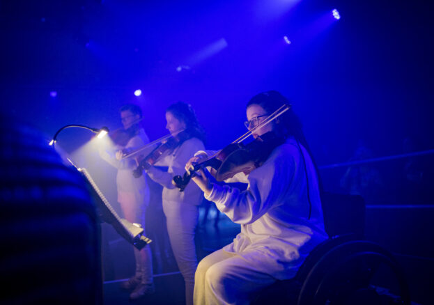 three musicians wearing white and performing with string instruments