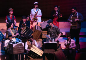 Wind musicians dressed in sailor costumes and performing on wooden crates