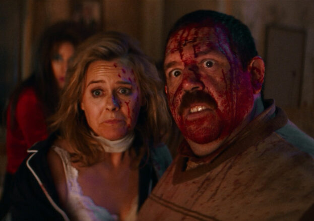 A man and a woman look up, covered in blood.