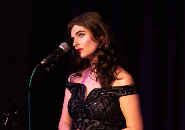 Natalie Ciufo - singer - stares into the audience, about to sing, wearing a sparkly dress. Ember's Spooky Season Sizzler at Cultplex