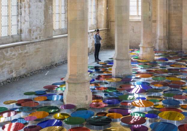 A person in a chapel looking at multicoloured circular discs 