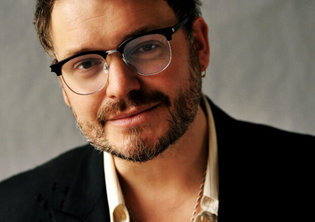 A photograph of a white man wearling glasses.