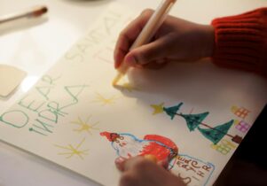 A child's hand writing a Christmas Card Kids Christmas Crafting at Springwell