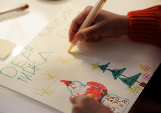 A child's hand writing a Christmas Card Kids Christmas Crafting at Springwell