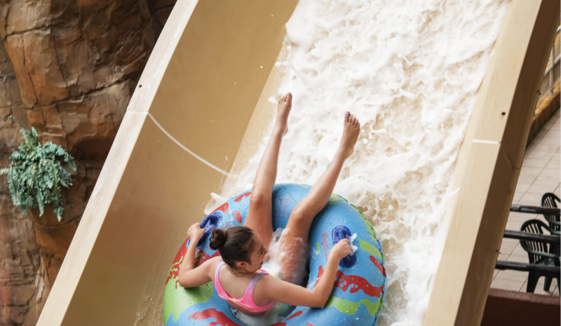 Girl on a blue rubber ring riding a waterslide