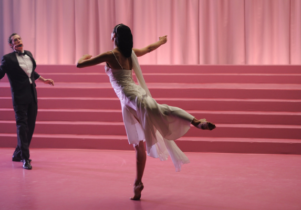 A man and woman dance in a pink theatre.