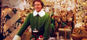 A man is dressed as an Elf in a decorated department store.