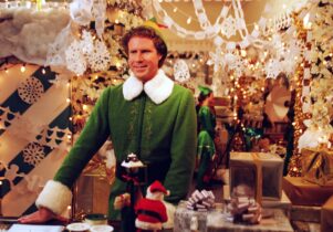 A man is dressed as an Elf in a decorated department store.