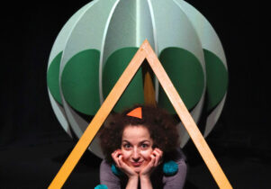 Image of actor within the set, wearing green pom poms. Soft or spiky? at z-arts