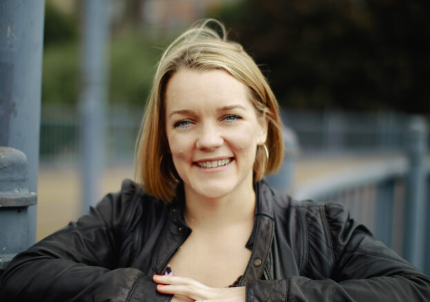 Author Rachel Bower leaning on metal railings looking towards the camera