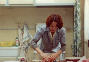 A woman with red hair is working in the kitchen.